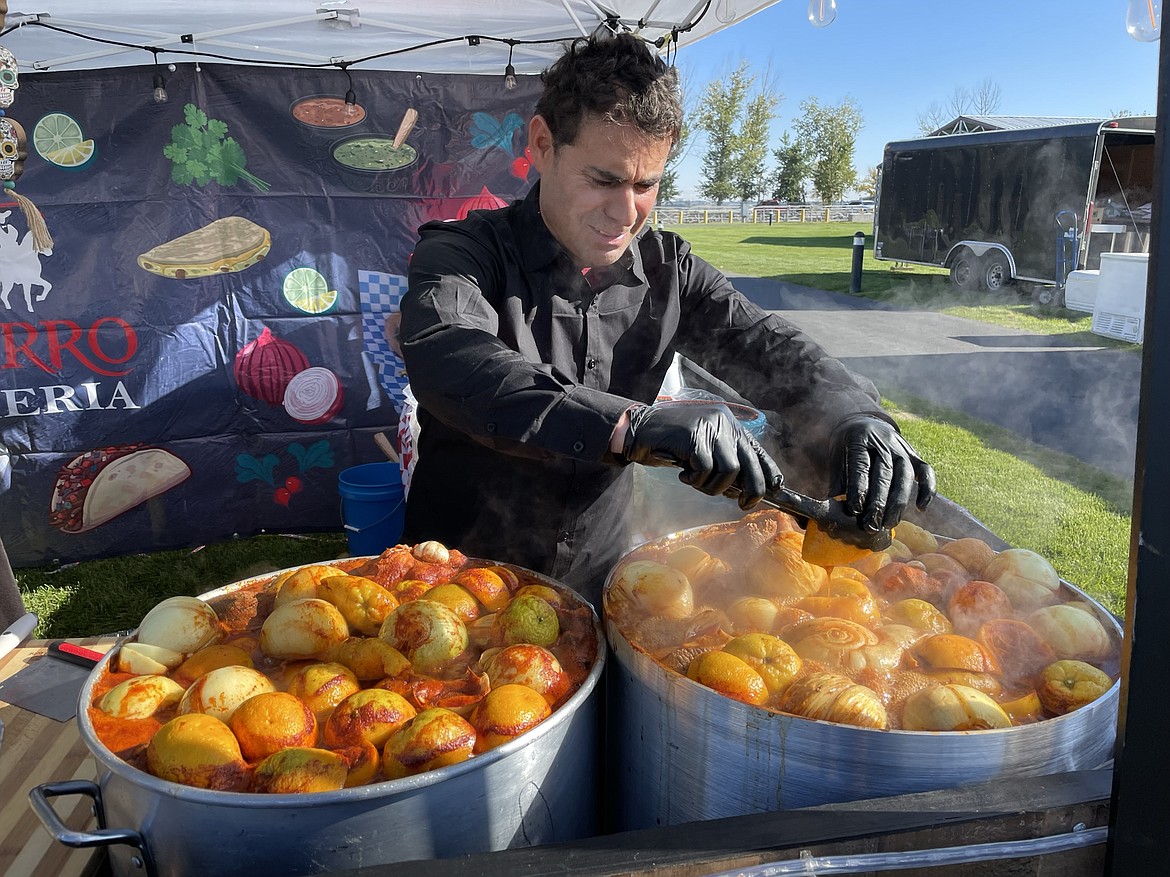 Santos Vidrio, owner of El Charro Birreria in Ephrata, squeezes an orange into a giant pot of birria, a stewed Mexican meat dish frequently used to make tacos, as one of the food vendors at the Moravida Festival at the Grant County Fairgrounds on Saturday.