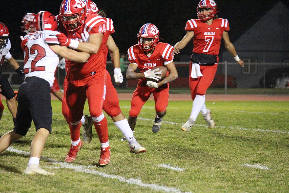 Following the lead of his blockers, Othello’s Alex Mendez (21) takes the handoff in the Huskies 35-10 over East Valley (Yakima).