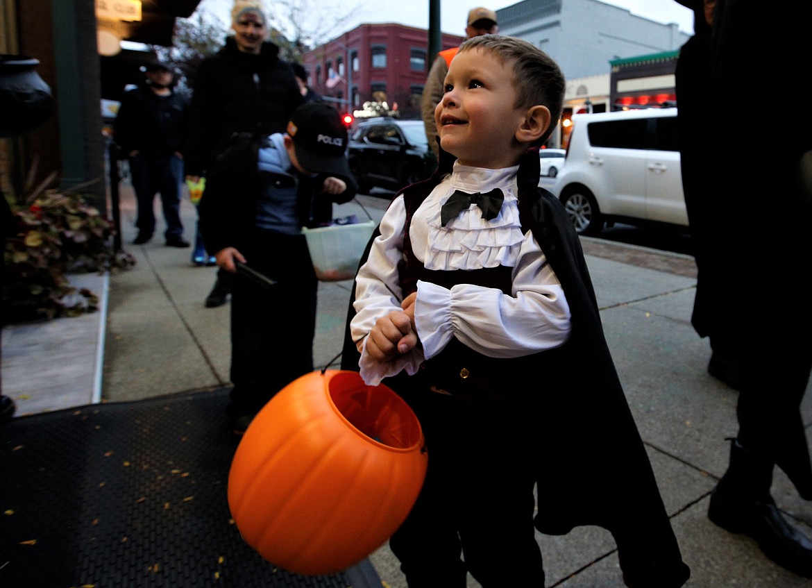 Vincent Ramirez looks up and smiles as he goes trick-or-treating on Sherman Avenue in Coeur d'Alene on Monday. Hundreds of adults and kids went to downtown shops collecting Halloween candy.
