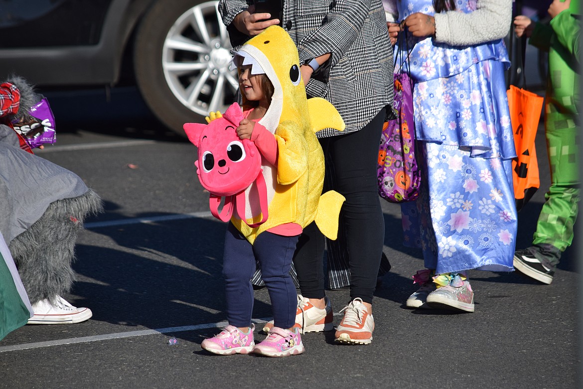 A little girl in a yellow shark costume stands in the middle of Third Avenue during the Harvest Festival in downtown Moses Lake on Saturday.