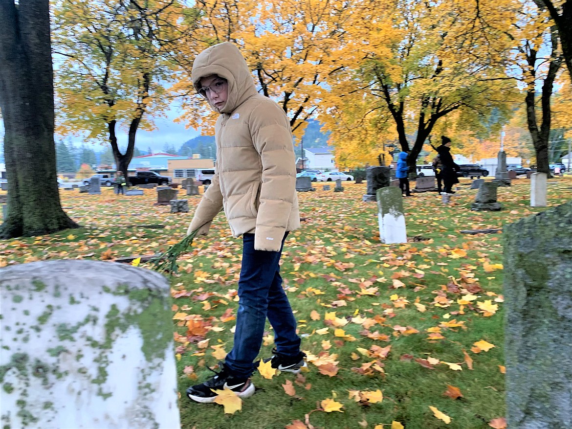 Holy Family Catholic School student Jaxon Mauro looks for a specific gravesite at St. Thomas Catholic Cemetery on Wednesday.