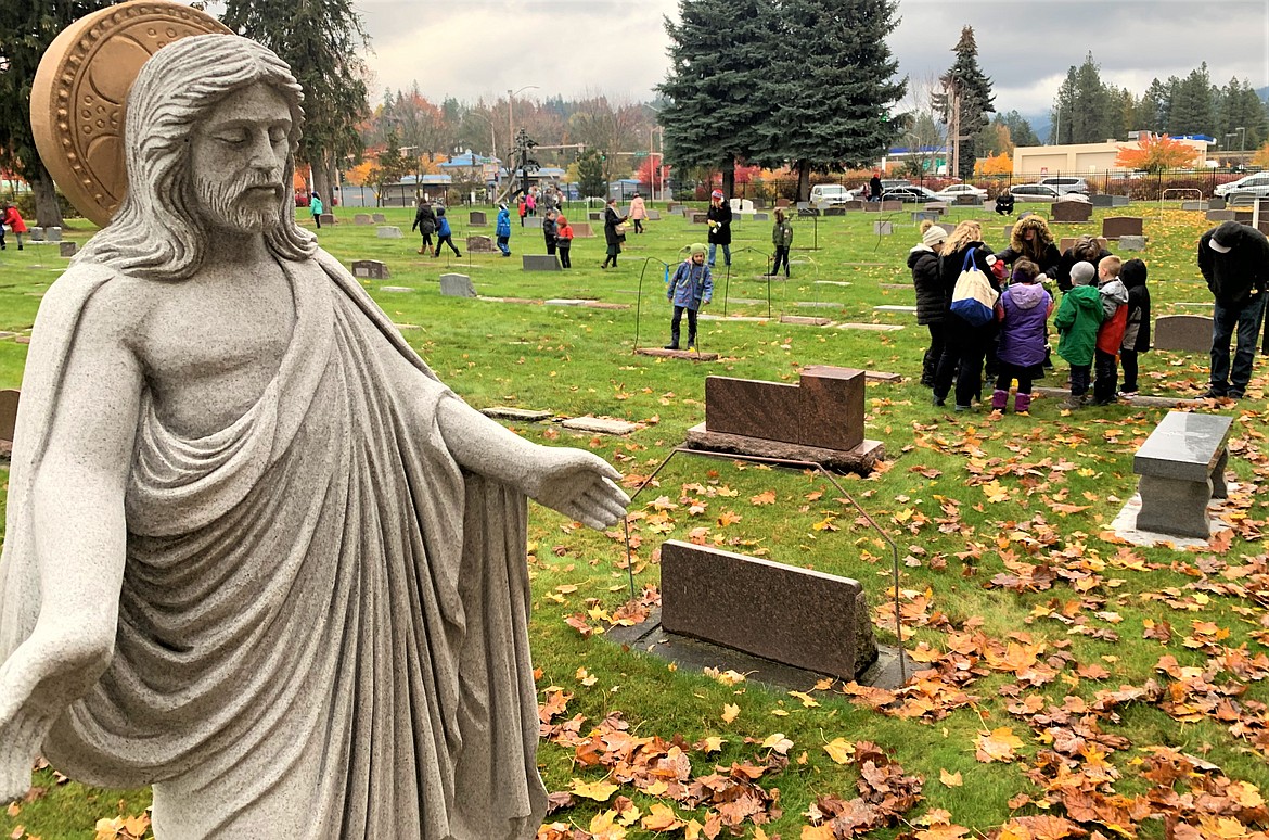 A statue of Jesus Christ stands over Holy Family Catholic School as they visit St. Thomas Catholic Cemetery on Wednesday, which was All Souls Day.