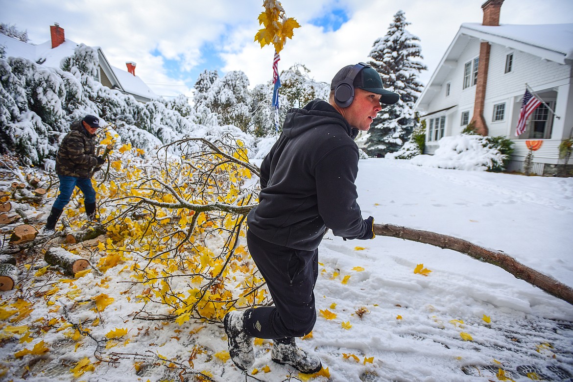 Chet Todd and Ron Runnels, back left, clean up downed tree limbs and debris outside Runnels' property on Fifth Avenue East in Kalispell on Thursday, Nov. 3. (Casey Kreider/Daily Inter Lake)