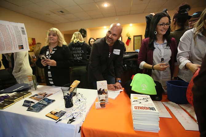 Jason Coombs, CEO and founder of Brick House Recovery, signs books and visits with guests during an open house. Brick House Recovery now shares a building with Ideal Option, where both entities provide complementary recovery and treatment services for those struggling with substance abuse and addiction.