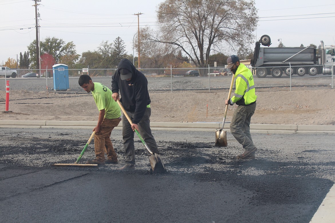Crews work the freshly-applied asphalt in the parking lot at the new Moses Lake Food Bank facility on Grape Drive.