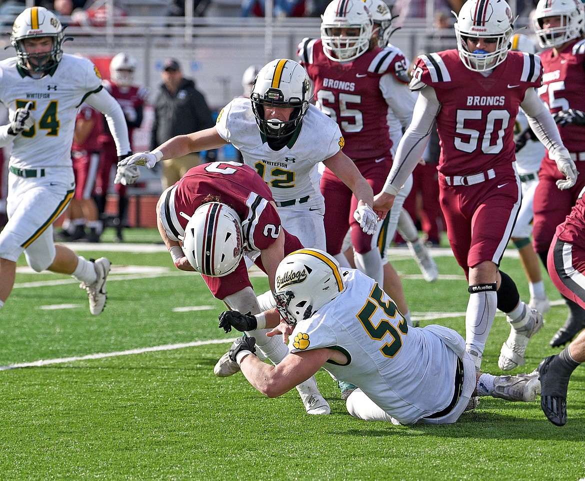 Whitefish's Kai Nash (55) and Luke Moses (12) combine for a tackle against Hamilton's Tyson Bauder in the State A quarterfinal game on Saturday in Hamilton. (Whitney England/Whitefish Pilot)