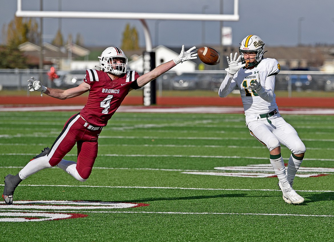 Bulldog Mason Kelch makes a catch just past the outstretched arm of Broncs' Hunter Stewart in the Class A state quarterfinal game on Saturday in Hamilton. (Whitney England/Whitefish Pilot)
