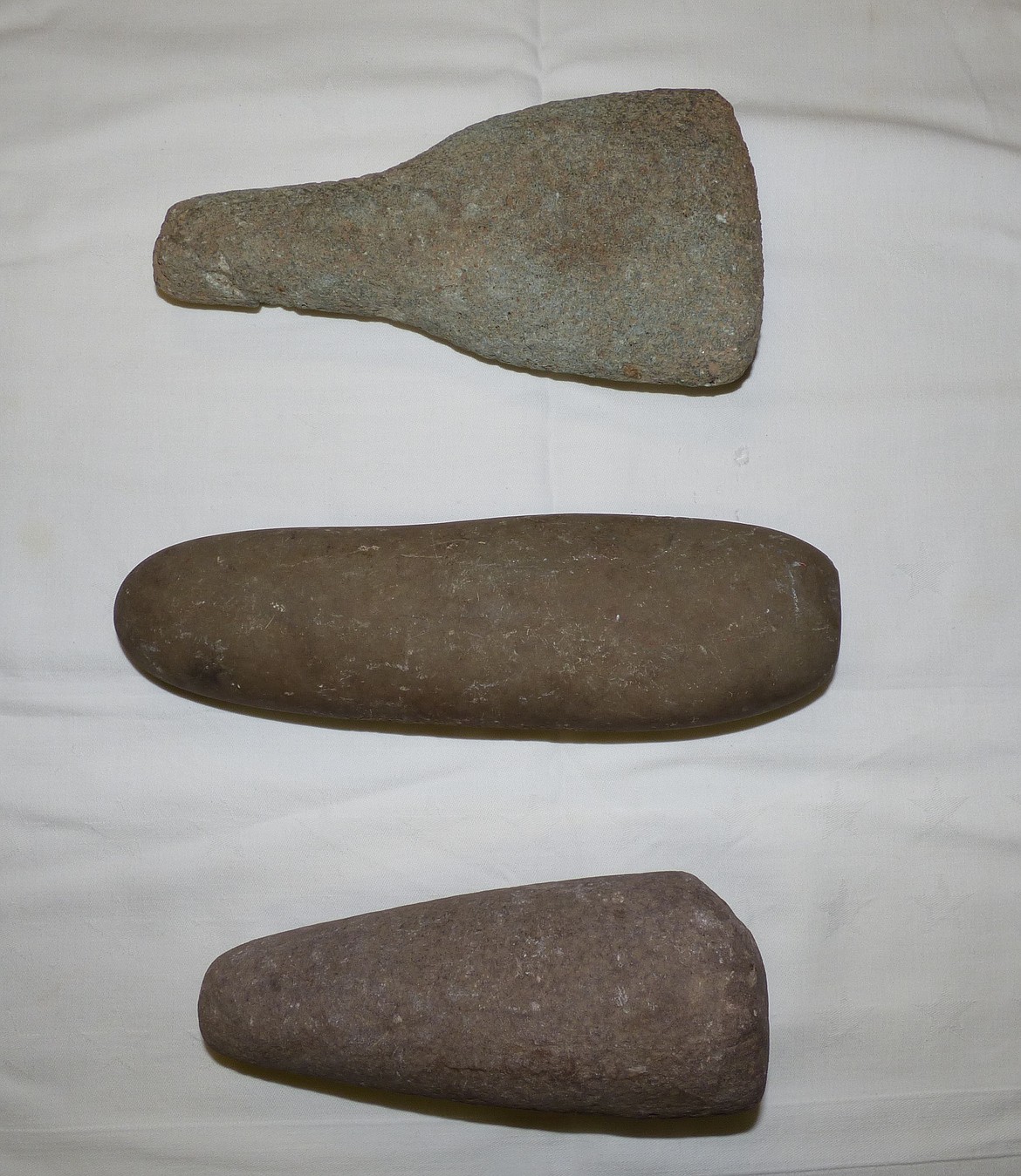 The paddle shaped rock in the top of the photo is an ice breaking tool. The long rock in the middle of the photo is a grinding tool. The rock on the bottom of the photo is a pestle, and was used in a bowl shaped rock