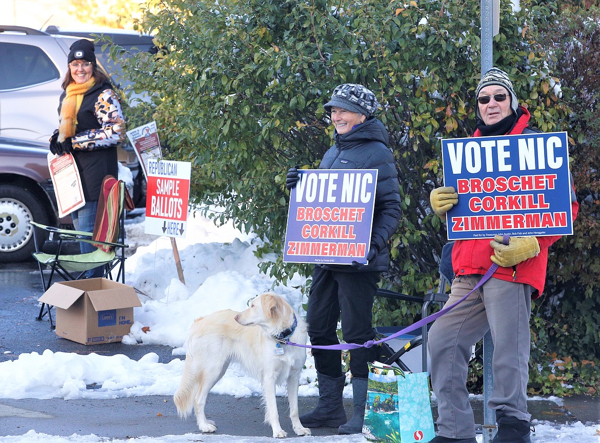 Neil Nemec, right, and Mary Sanderson, center, joined by Jazzmin the dog, encourage voters to support Brad Corkill, Tarie Zimmerman and Pete Broschet for the North Idaho College Board of Trustees while Lisa Whitehead, Republican committeeman of precincts 418 and 419, offers sample ballots outside St. Thomas Parish Center on Tuesday.