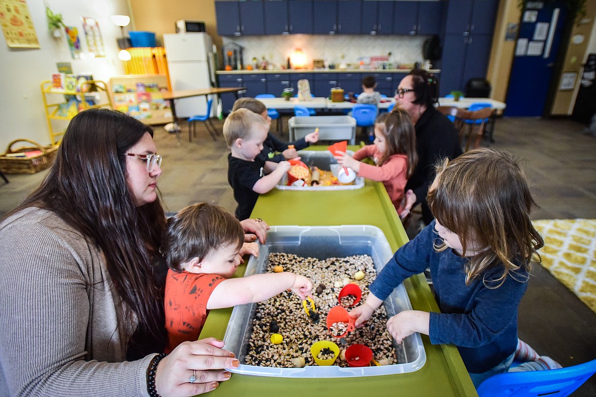 Owner Ashley Levesque and her assistant Korri Volen, back right, assist kids at a sensory table at The Hive Daycare inside Peterson Elementary School in Kalispell on Wednesday, Nov. 9. (Casey Kreider/Daily Inter Lake)