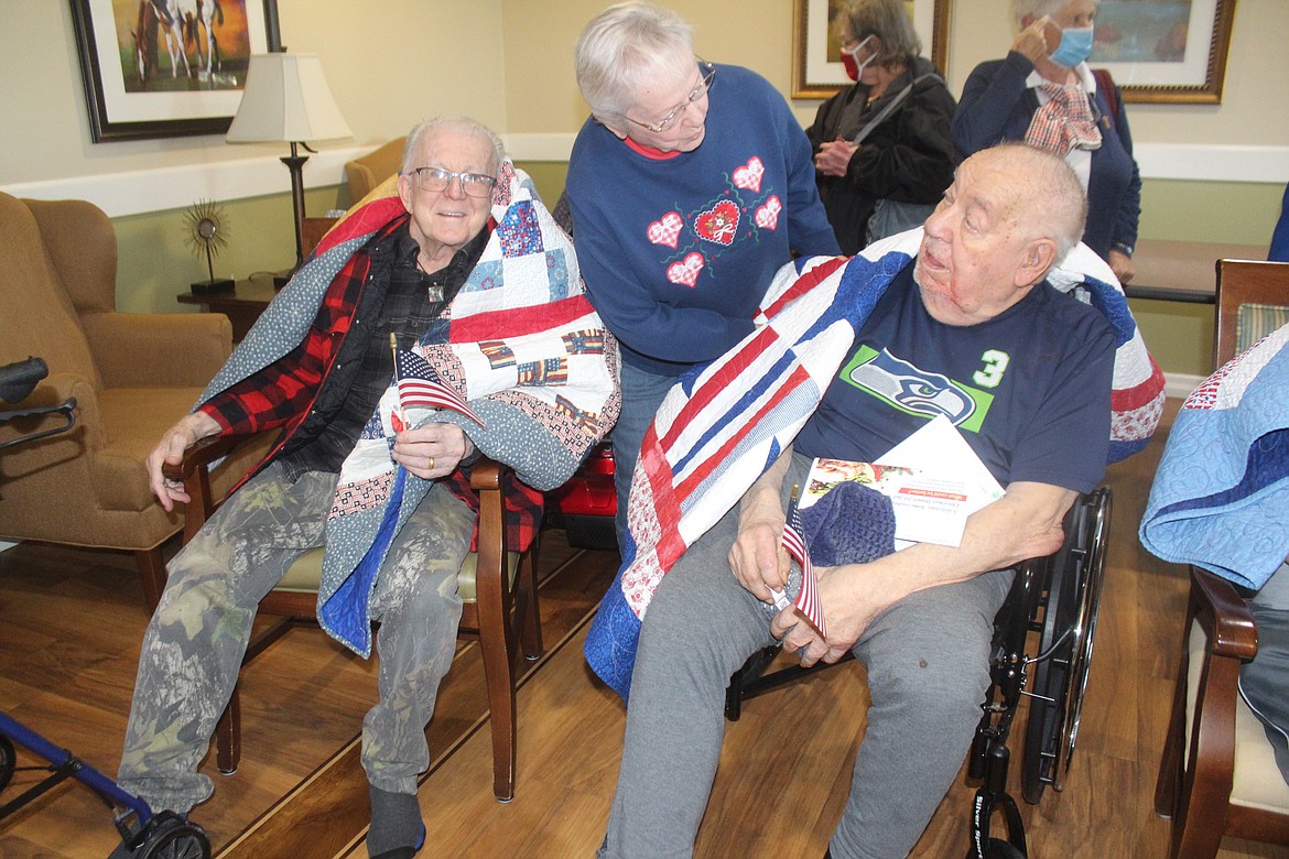 Brookdale Hearthstone veterans, wearing their new quilts, talk with a Basin Piecemakers Guild member.