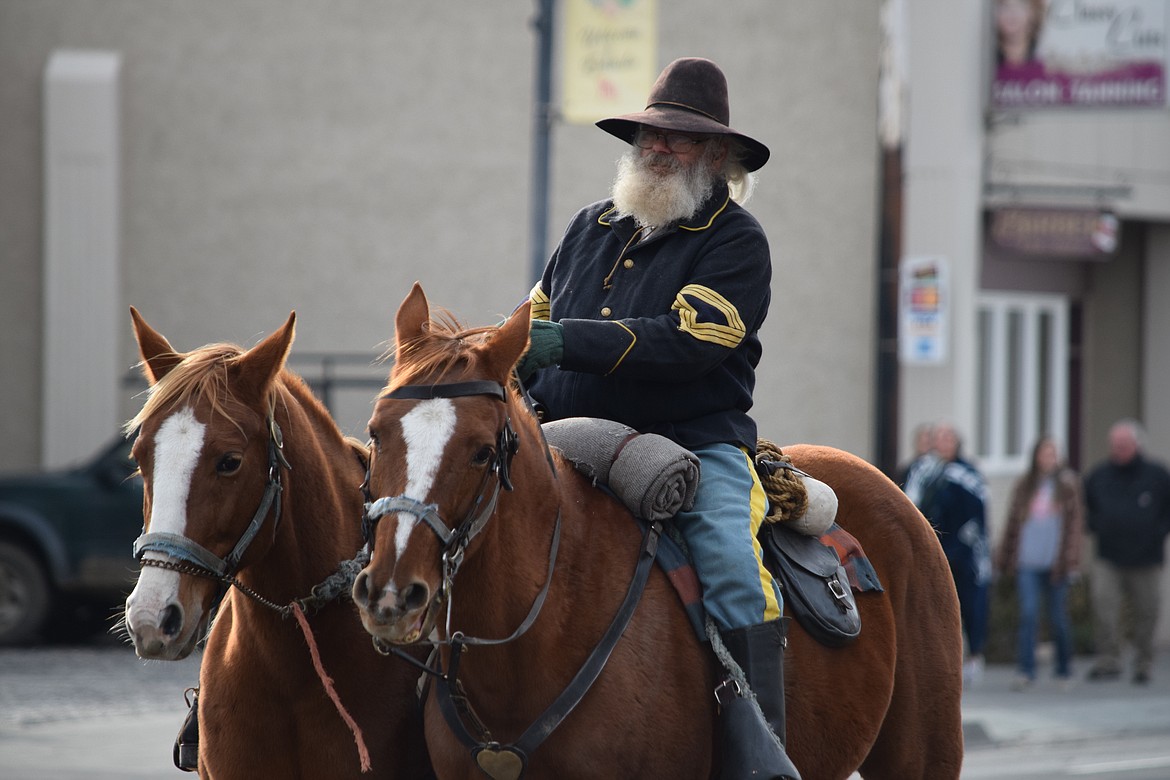Ken Nash, an Ephrata resident and member of the Washington Civil War Association, rides next to a funeral horse with an empty saddle and backward boots in the stirrups, during the annual Veterans Day Parade in Ephrata on Friday.