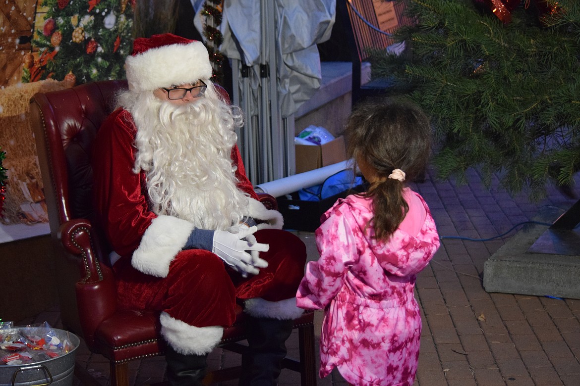 Santa  – Also known as Jacob Shank, son of Edward Jones financial advisor and Downtown Moses Lake Association Vice President James Shank – listens as a child describes what she wants for Christmas. “There won’t be any gifts, but Santa will be taking orders,” James said.