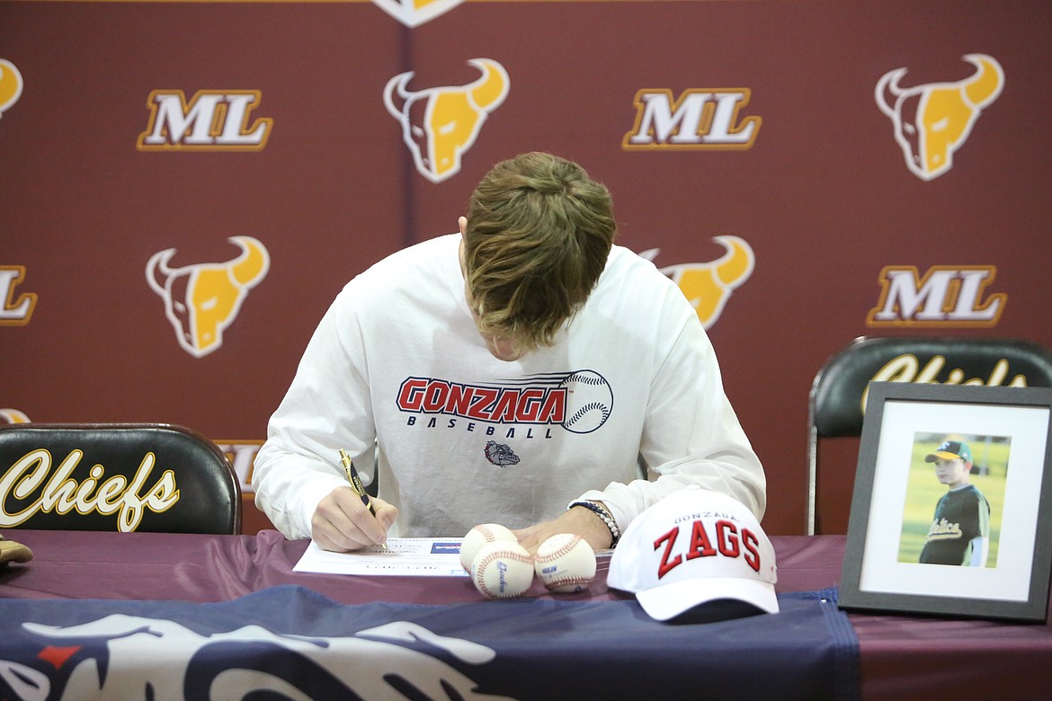 Right-handed pitcher Michael Getzinger signs his ceremonial National Letter of Intent on Friday at the Moses Lake High School gym.