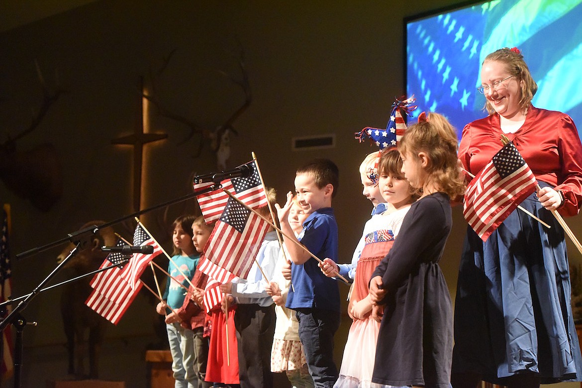 Kootenai Valley Christian School kindergarten teacher Rachel Mitchell hands out American flags to her students at the Veterans Day program on Friday, Nov. 11, at the Libby Christian Church. (Scott Shindledecker/The Western News)