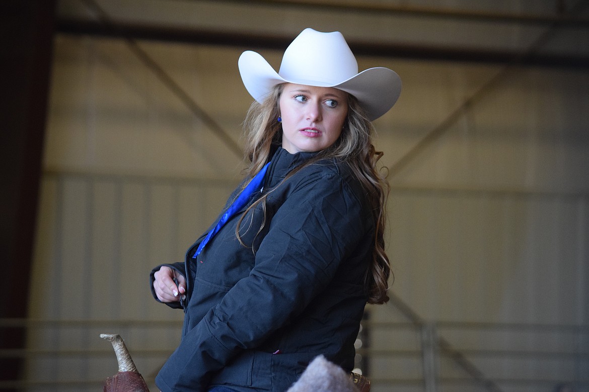 Contestant Milie Cobb of Ephrata zips up her coat following a warmup exercise during the horsemanship portion of the Miss Moses Lake Roundup competition on Saturday. Cobb was second runner up.