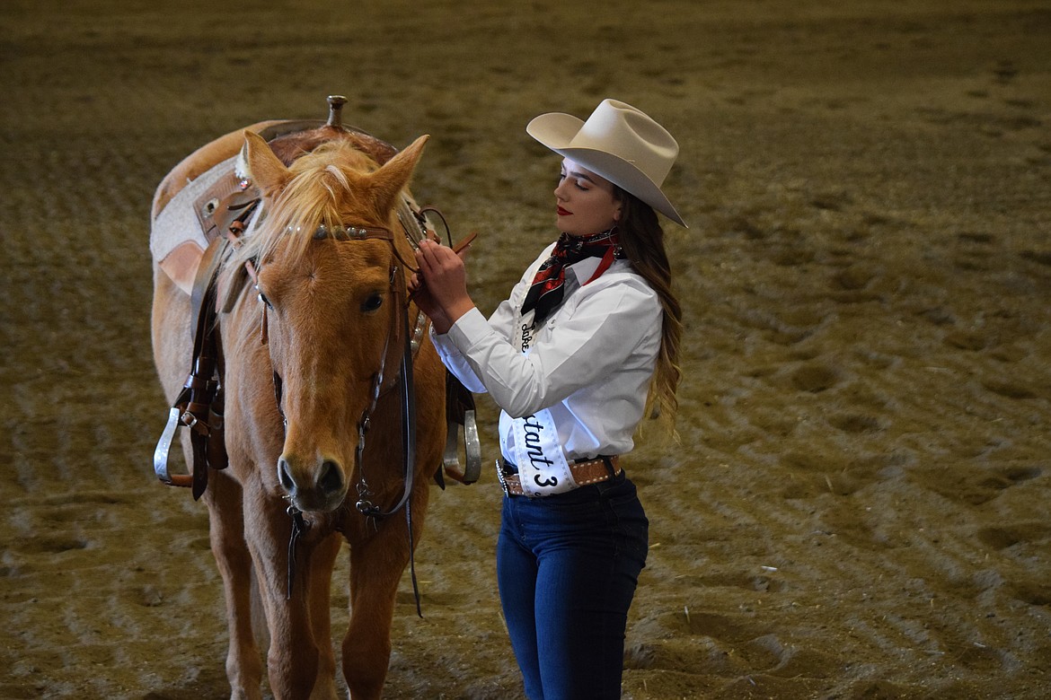 Miss Moses Lake Roundup contestant Jenna Penrose buckles her horse’s bridle following a series of questions from pageant judges.