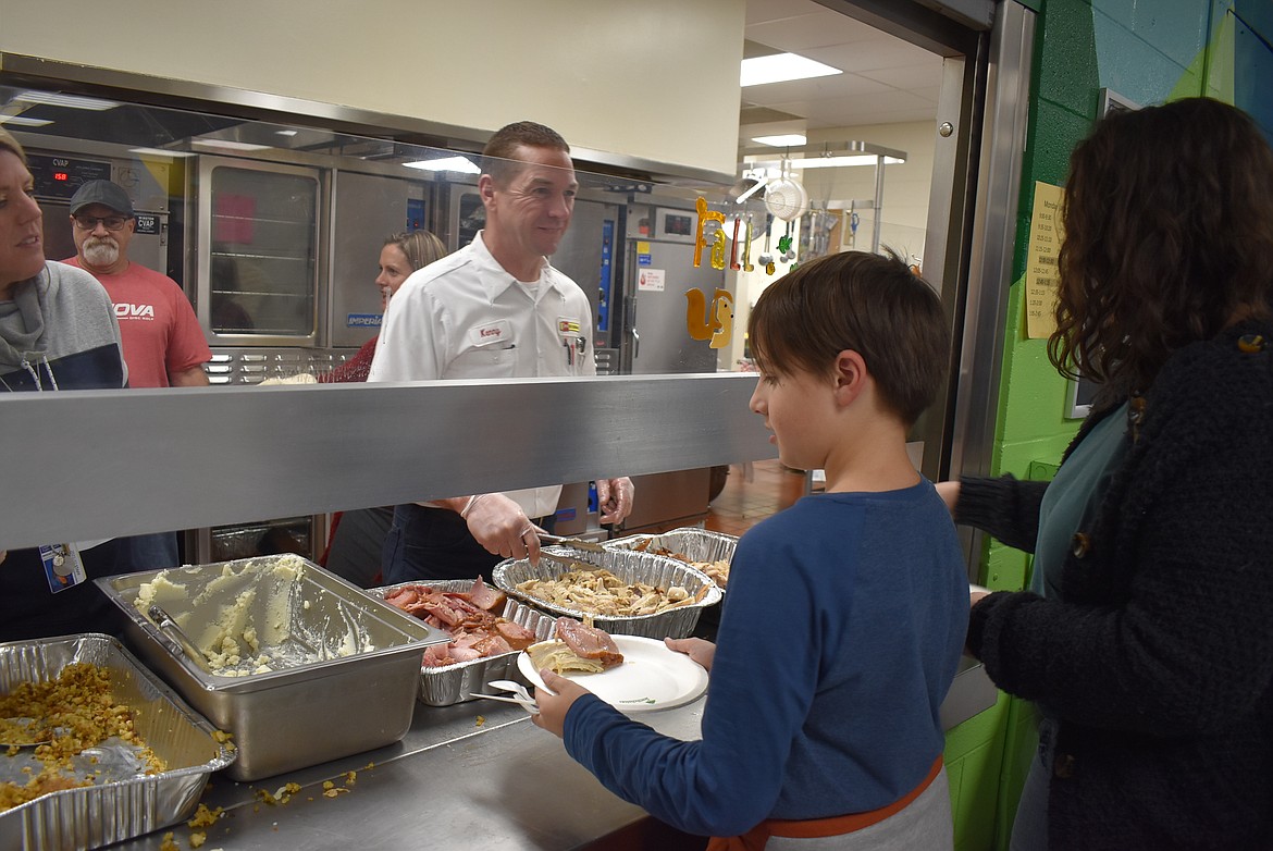 Kenny Carver, manager of the Les Schwab Tire Center in Hayden, helps serve dinner from the kitchen Wednesday evening during Lakesgiving at Lakes Middle School.