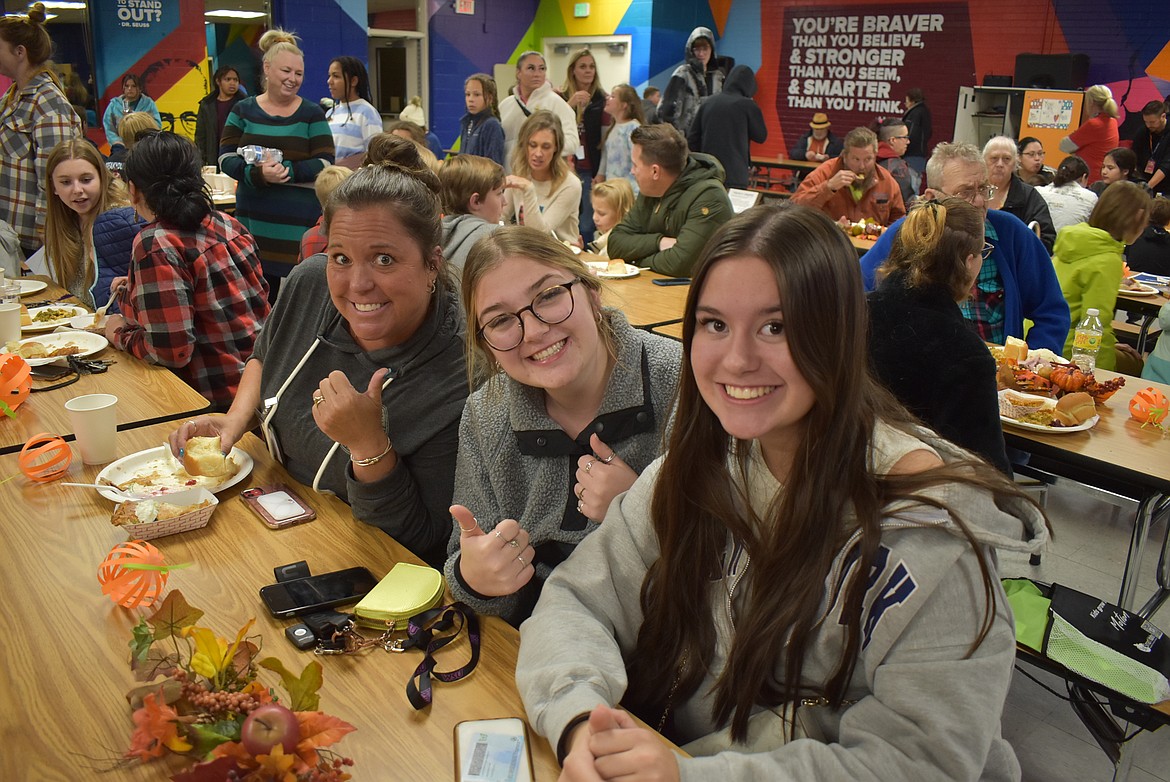 Lakes Middle School building secretary Michele Torres, left, Clara Johnson, center and Alexandra Torres smile for the camera as they enjoy a community Thanksgiving meal Wednesday evening during Lakesgiving.