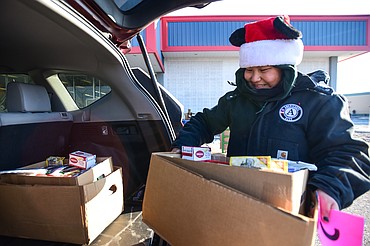 Emma Sweeney, a volunteer with AmeriCorps, loads a box of holiday food items into the back of a client's vehicle during the Flathead Food Bank's Thanksgiving distribution on Friday, Nov. 18. Around 800 families pre-registered for the distribution, which does not account for a two hour window set aside for families who were not able to pre-register. (Casey Kreider/Daily Inter Lake)