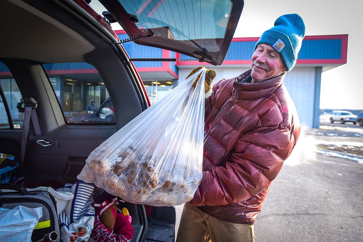 Flathead Food Bank volunteer Dave Williams loads a bag of potatoes into the back of a client's vehicle during the food bank's Thanksgiving distribution on Friday, Nov. 18. Around 800 families pre-registered for the distribution, which does not account for a two hour window set aside for families who were not able to pre-register. (Casey Kreider/Daily Inter Lake)