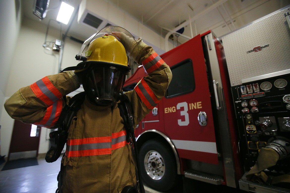 Lake City High School senior Matt Willhite straps on his fire helmet Wednesday while on shift at Fire Station 3 in Coeur d'Alene. Matt, 17, is one of five students going through the Coeur d'Alene Fire Department's cadet program this semester.