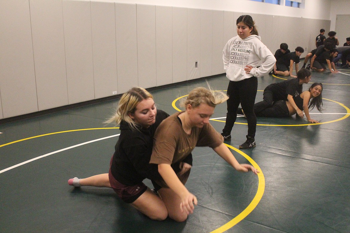Quincy wrestlers practice their moves under the watchful eye of assistant coach Kim Avalos (in white).