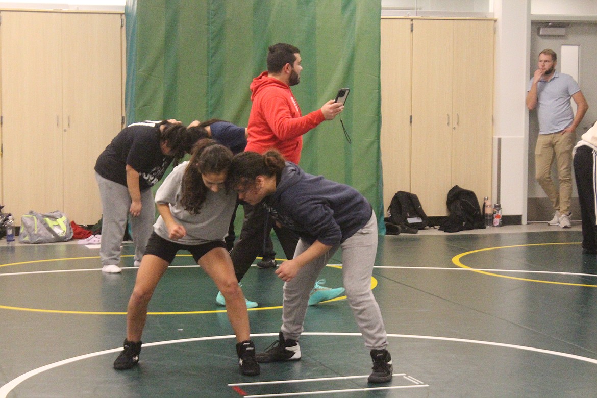 Quincy wrestlers work on their moves during practice, while girls head coach Devan Silva (in red) keeps time.