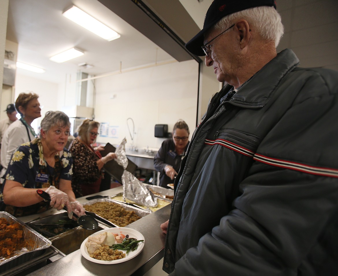 Kitchen volunteer Tracy Vic chats with David Gertje of Coeur d'Alene as she helps fill plates during the American Legion Post 143 community Thanksgiving meal in Post Falls on Saturday.