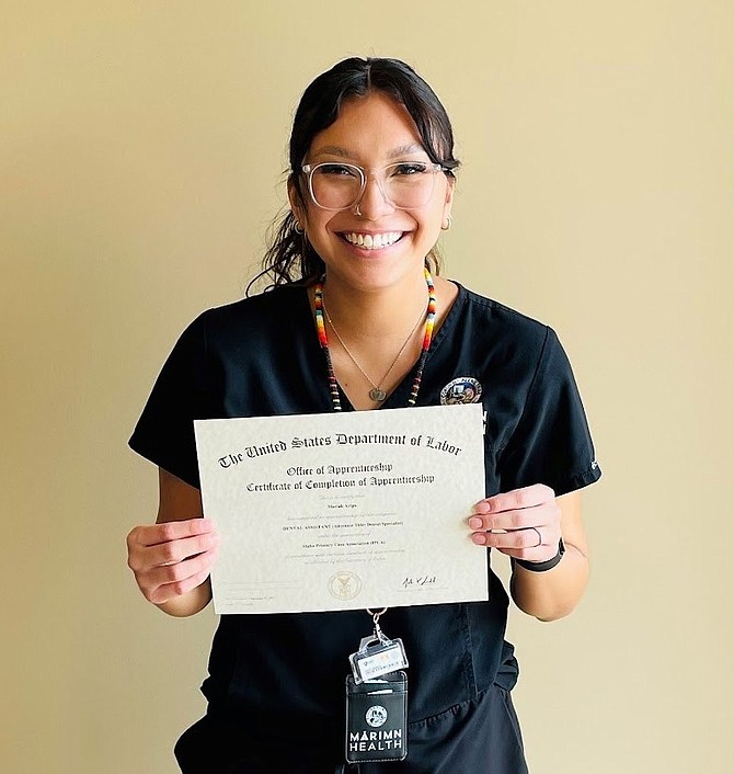 Mariah Aripa holds her dental assisting apprenticeship completion certificate.