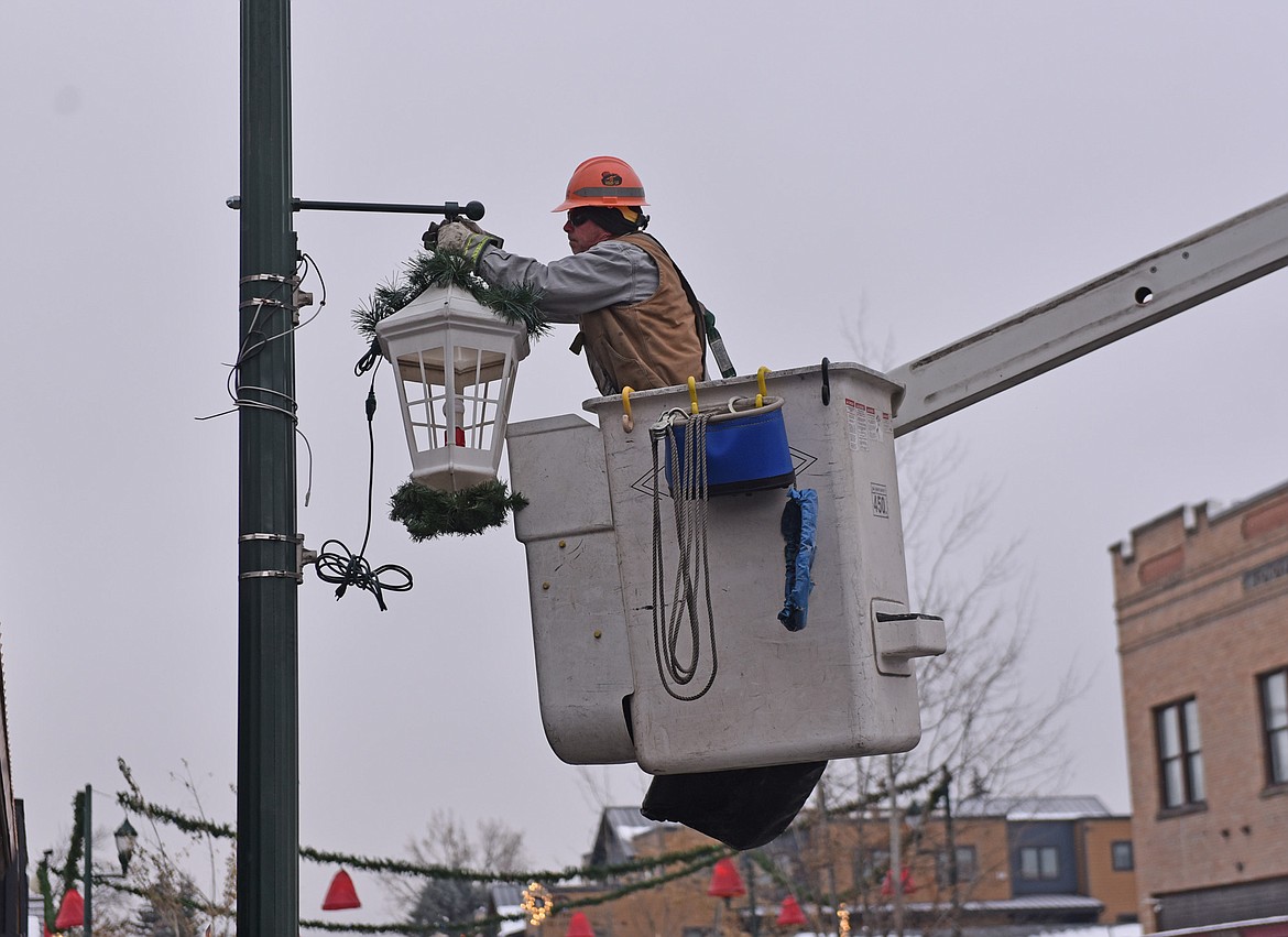 A crew member from FEC hangs a lantern Sunday morning. (Julie Engler/Whitefish Pilot)