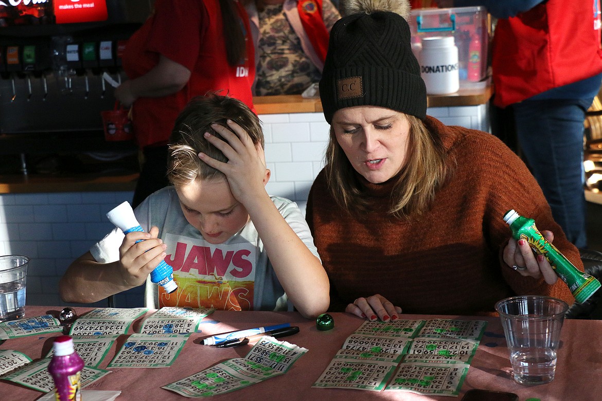 A young family member concentrates as he searches for a bingo number that was called during a Turkey Bingo game on Saturday.