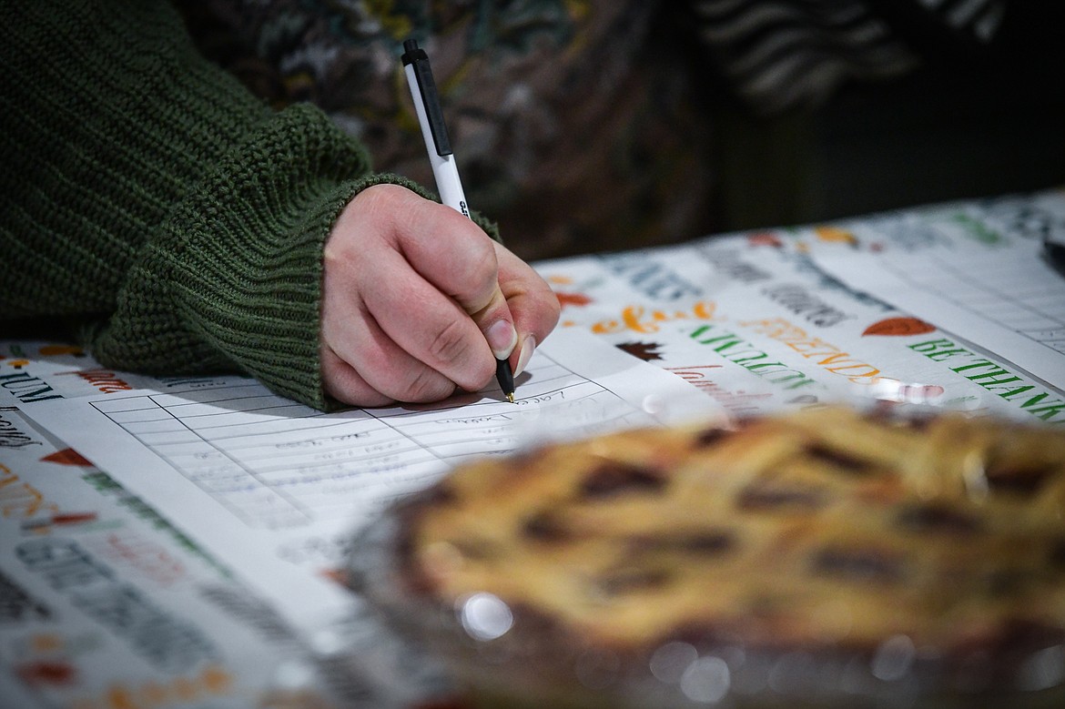 An attendee bids on a pie during the silent auction at Light Up Evergreen & Pie Auction at Glacier Ace Hardware on Tuesday, Nov. 22. (Casey Kreider/Daily Inter Lake)