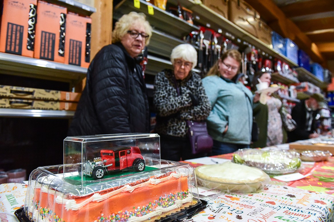 Attendees look over a row of pies, including a white cake donated by Vaughn Warriner, during the silent auction at Light Up Evergreen & Pie Auction at Glacier Ace Hardware on Tuesday, Nov. 22. (Casey Kreider/Daily Inter Lake)