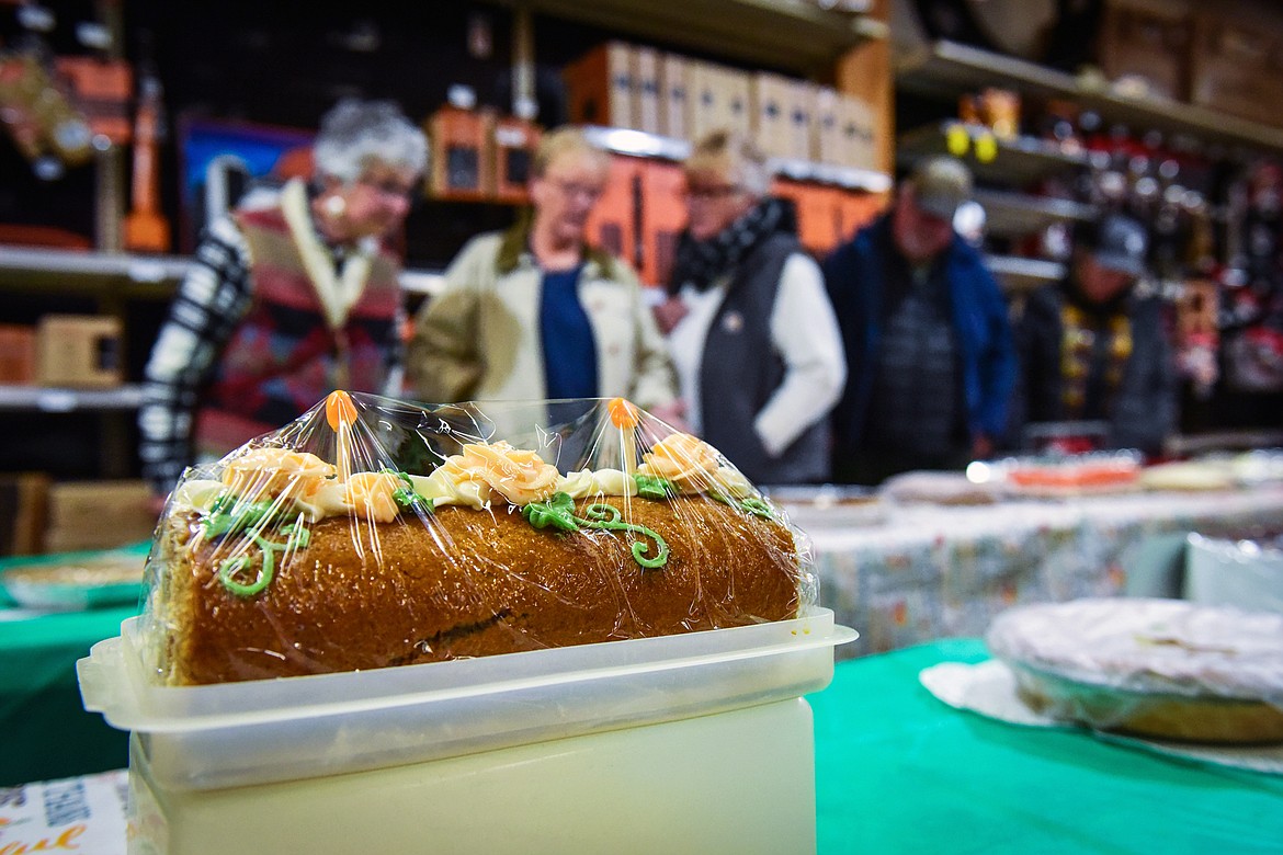 Attendees look over a row of pies, including a pumpkin roll donated by Northwest Montana Veterans Stand Down and Food Pantry, during the silent auction at Light Up Evergreen & Pie Auction at Glacier Ace Hardware on Tuesday, Nov. 22. (Casey Kreider/Daily Inter Lake)