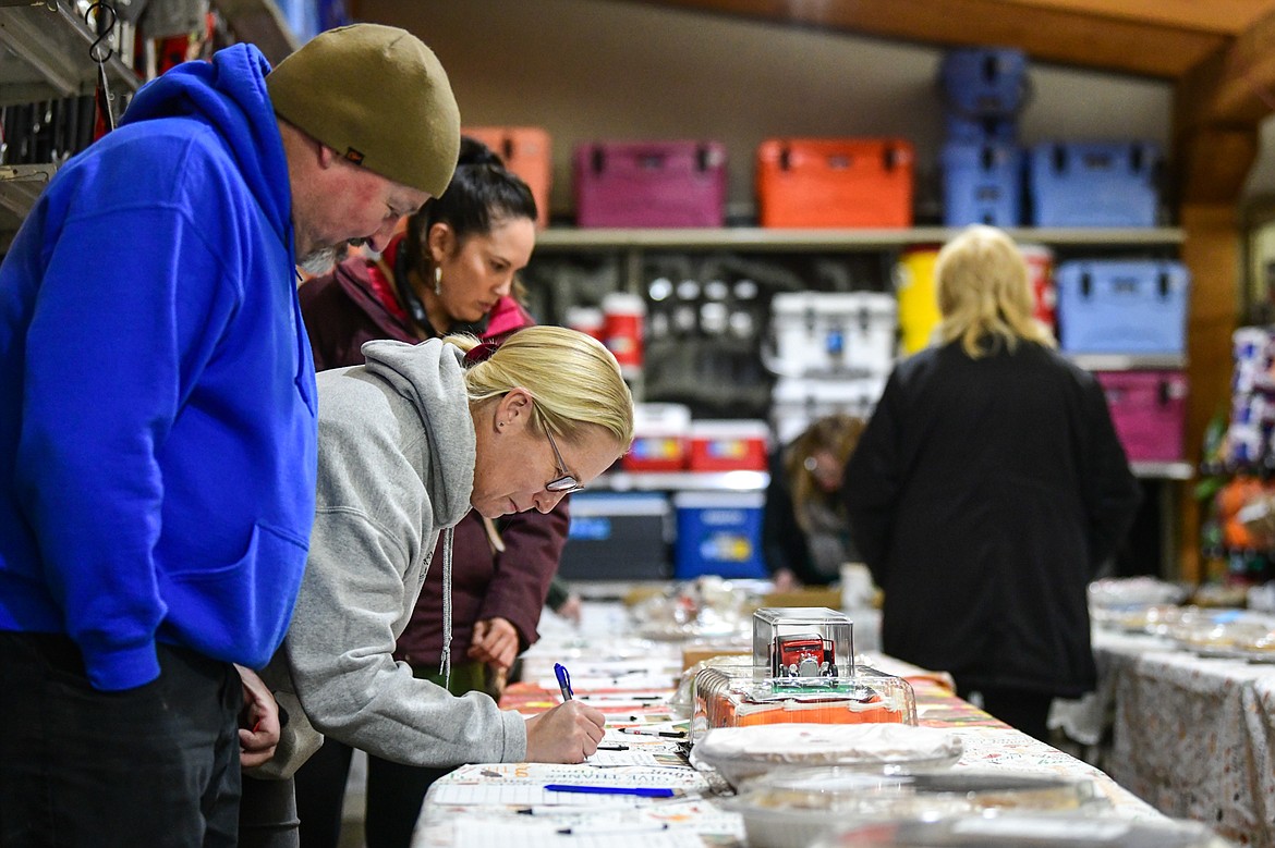 Attendees bid on pies during the silent auction at Light Up Evergreen & Pie Auction at Glacier Ace Hardware on Tuesday, Nov. 22. (Casey Kreider/Daily Inter Lake)
