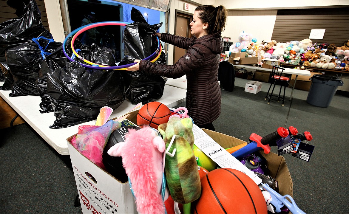 Alyssa Smith sets toys on a table being donated to Toys for Tots at its building at the Kootenai County Fairgrounds on Tuesday.