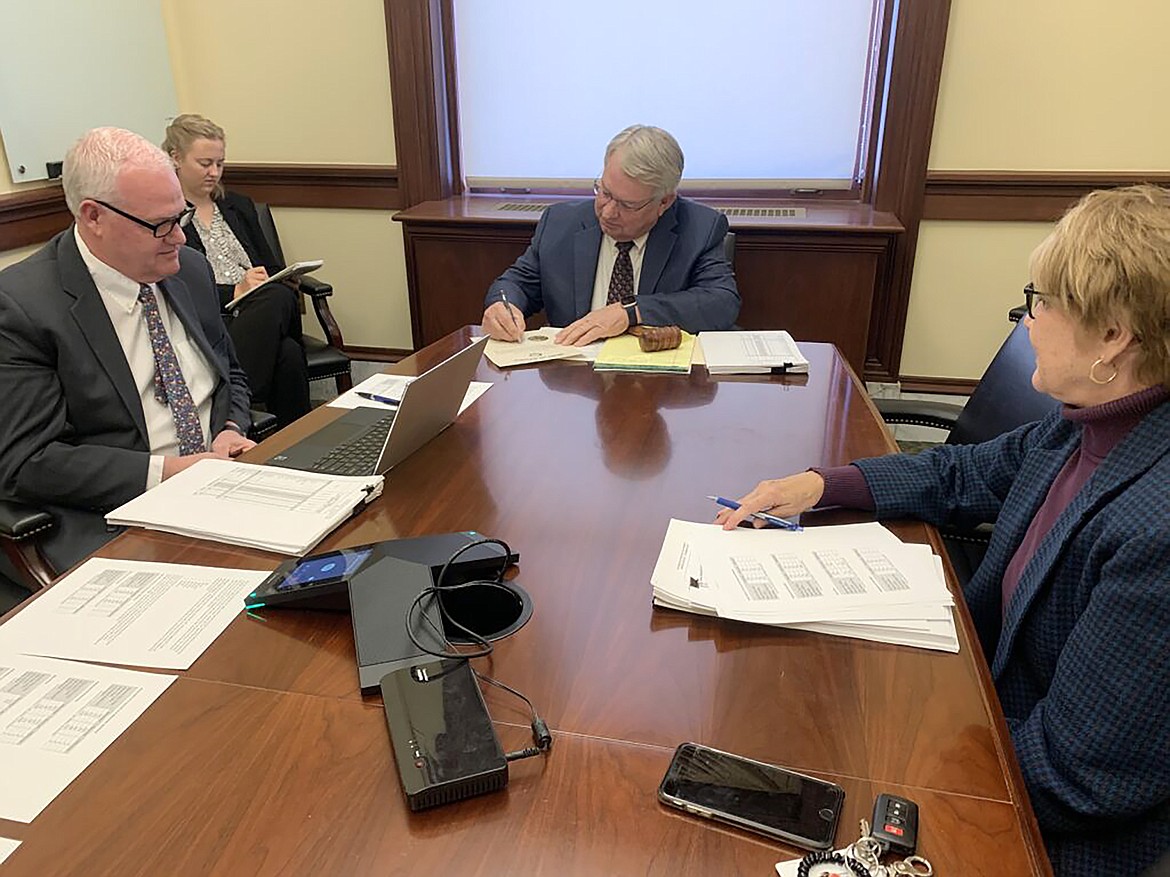 Idaho Secretary of State Lawerence Denney (center) signs documents certifying Idaho’s 2022 general election results on Nov. 23 as State Controller Brandon Woolf and State Treasurer Julie Ellsworth look on.