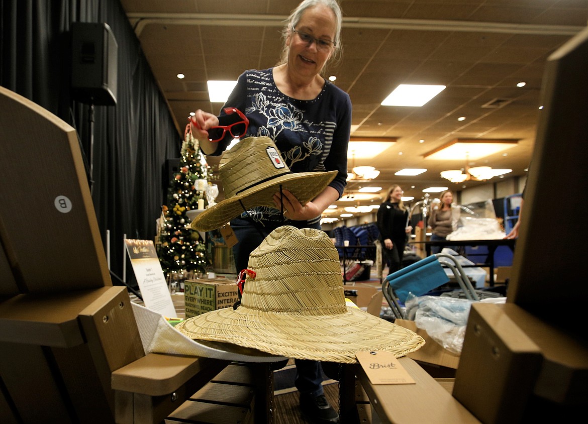Rhonda Budvarson sets a hat in the perfect place as she helps decorate the Super 1 Foods tree for the Festival of Trees on Friday at The Coeur d'Alene Resort.