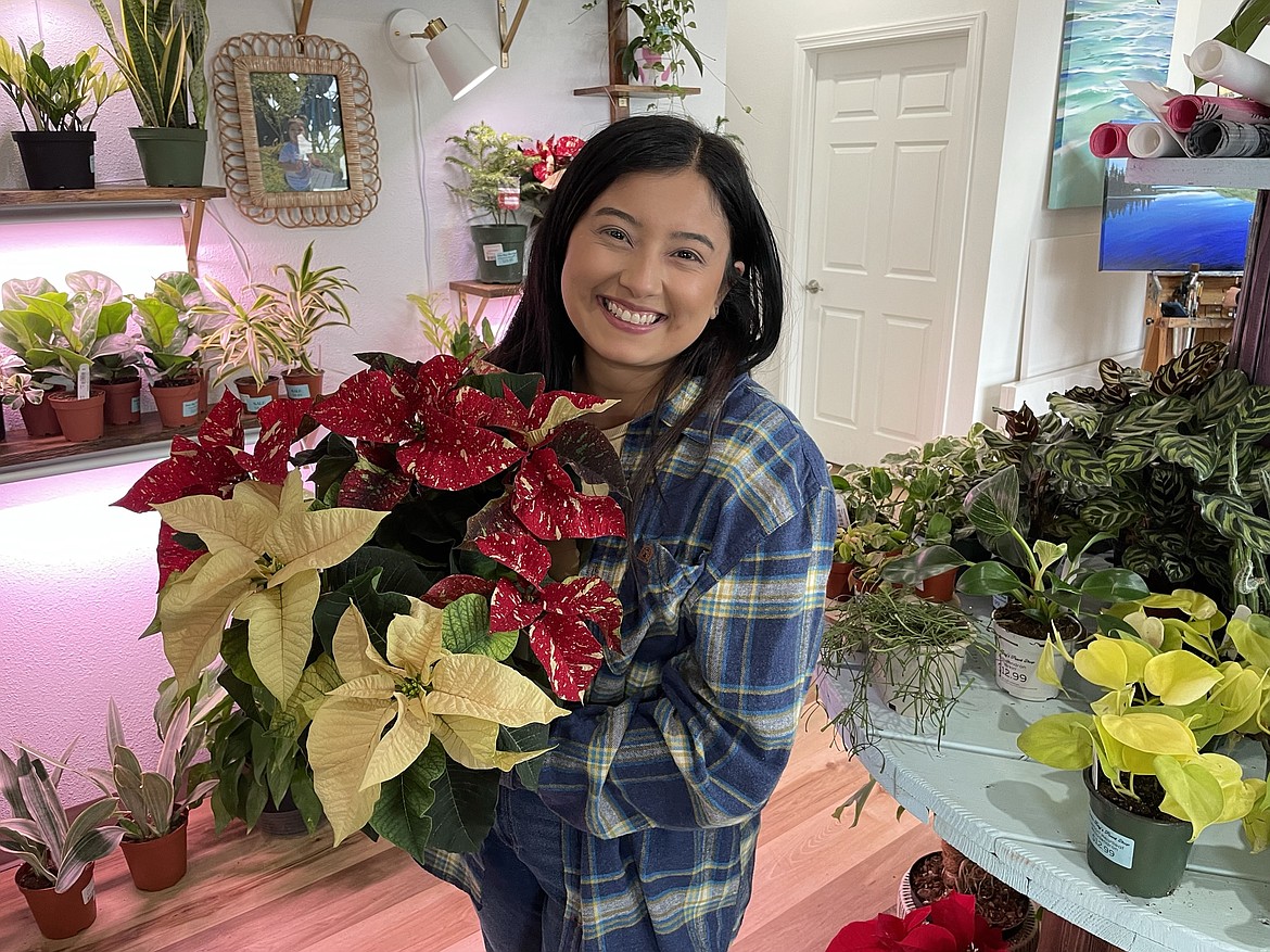 Breanna Verduzco, the owner of Evalee Ray’s Plant Shop in downtown Moses Lake, poses with a poinsettia — one of the many holiday plants she’s selling this season from her store.