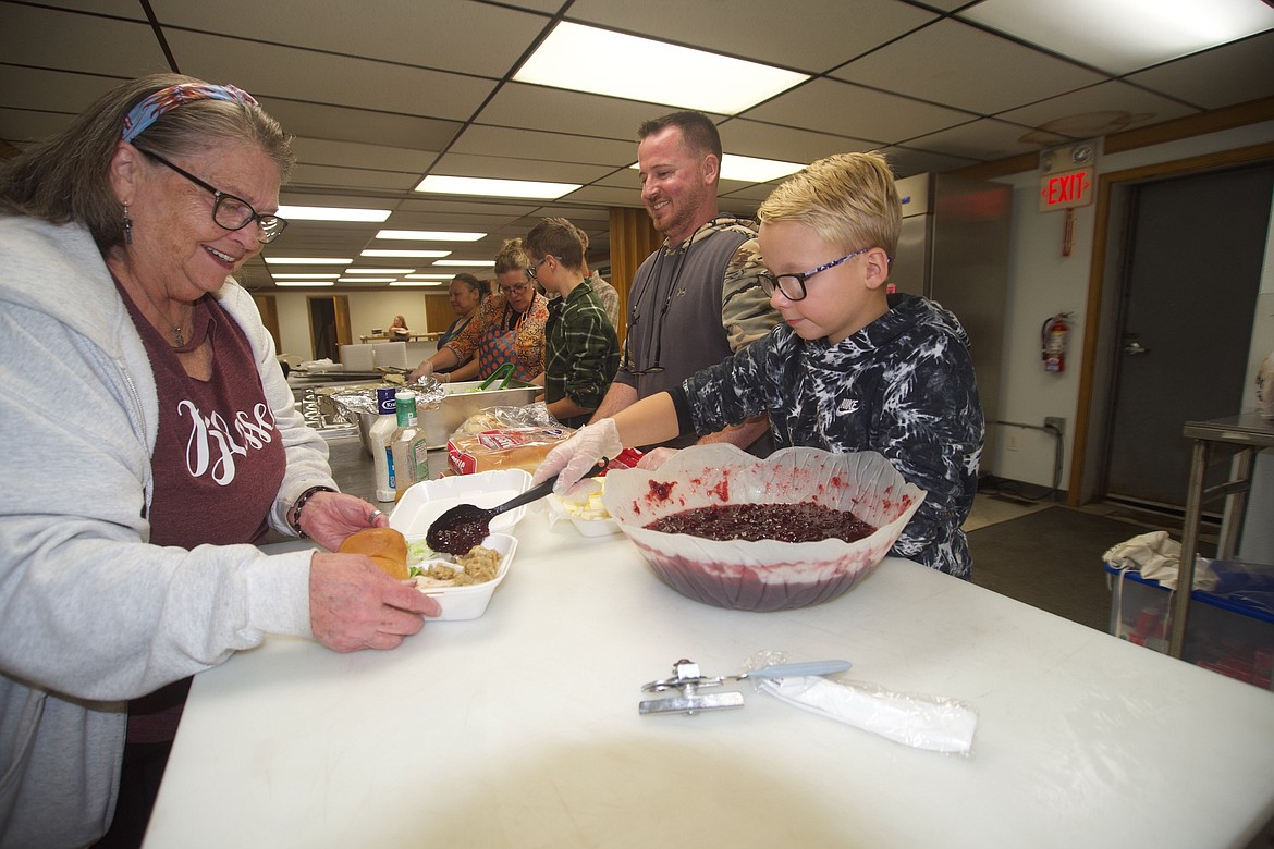 Easton Helmer was responsible for spooning out cranberry sauce at the Ronan Community Center Thursday. Volunteers served an estimated 250 dinners Thanksgiving Day. (Kristi Niemeyer/Lake County Leader)