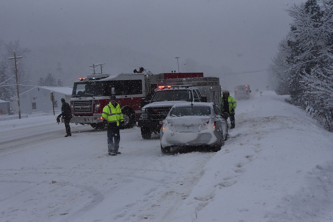 First responders work at the scene of a vehicle accident on Wednesday, Nov. 30. The vehicle went off the northbound lanes of U.S. 2, just south of Libby. The driver of the vehicle was taken to the hospital by Libby Volunteer Ambulance Service. Heavy, wet snow and temperatures in the high teens created slick roads across the region. (Scott Shindledecker/The Western News)