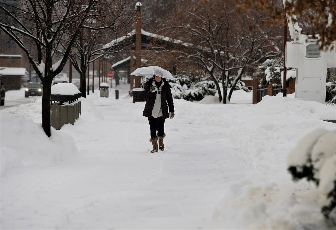 Karin Gray holds an umbrella for protection from the falling snow as she walks on Front Avenue in Coeur d'Alene on Wednesday.