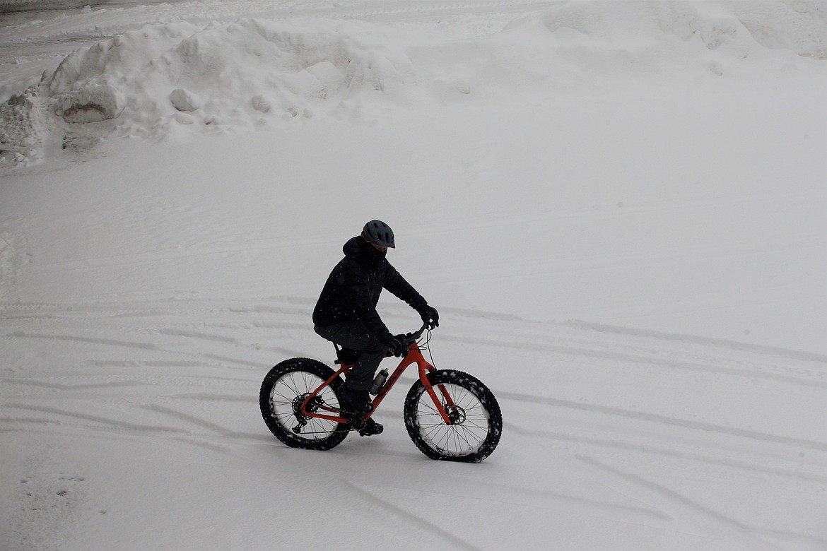 A cyclist rides through the snow-covered parking lot at McEuen Field on Wednesday.