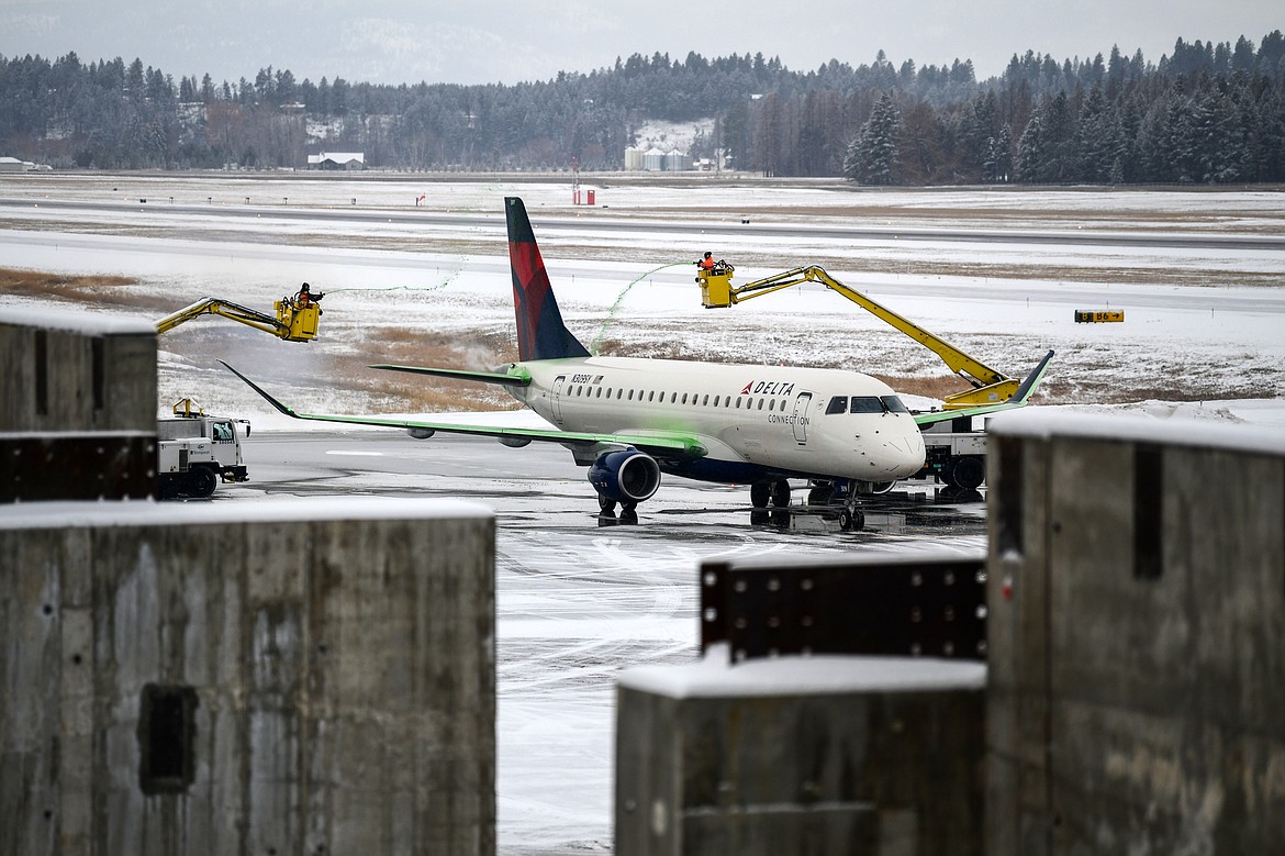 Workers de-ice a plane beyond the construction of concrete walls for Glacier Park International Airport's terminal expansion project on Wednesday, Nov. 30. (Casey Kreider/Daily Inter Lake)