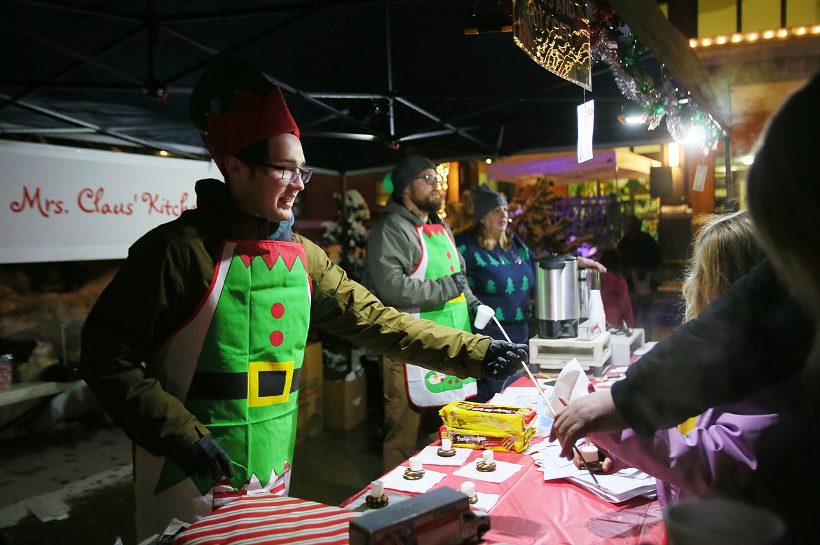 U-Haul regional manager and Mrs. Claus' helper Austin Standon hands out supplies for s'mores Friday evening during Post Falls' Winterfest and Plaza Market.