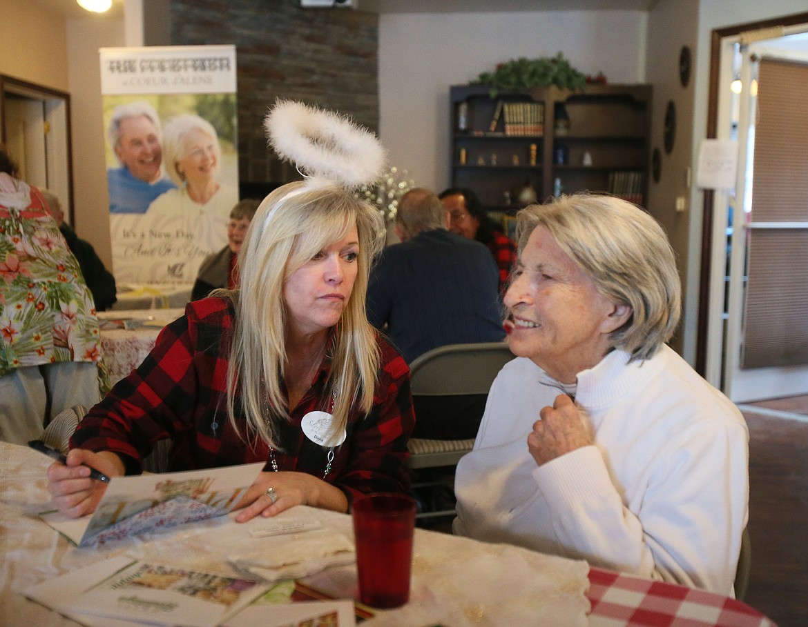 Silver Angels for the Elderly volunteer Diana Benham on Friday listens as Cokie Hough dictates a message for a Christmas card at Courtyard at Coeur d'Alene.