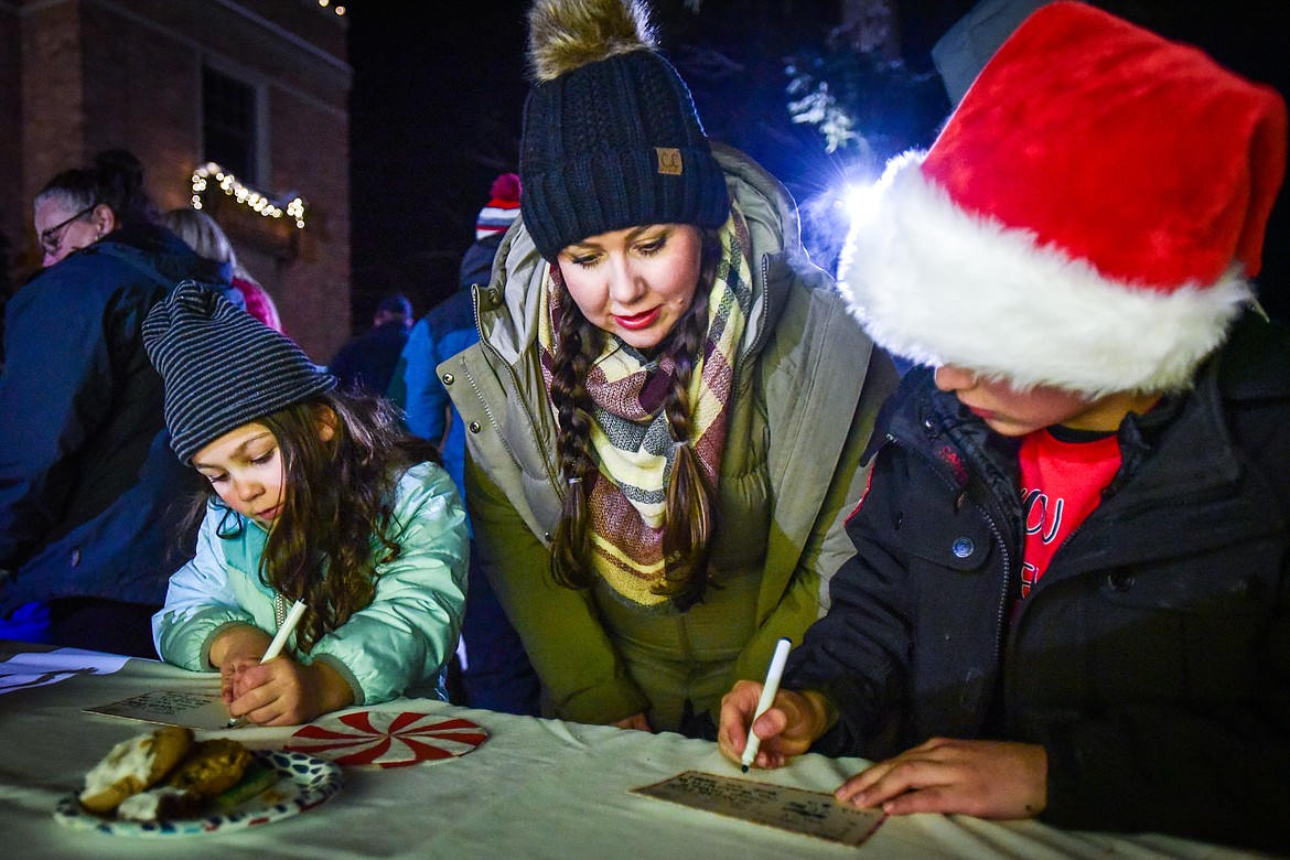 Maira and Travyn Naldrett write letters to Santa Claus with their mother Holly outside Johnson-Gloschat Funeral Home and Crematory during the Downtown Kalispell Holiday Stroll & Tree Lighting on Friday, Dec. 2. (Casey Kreider/Daily Inter Lake)