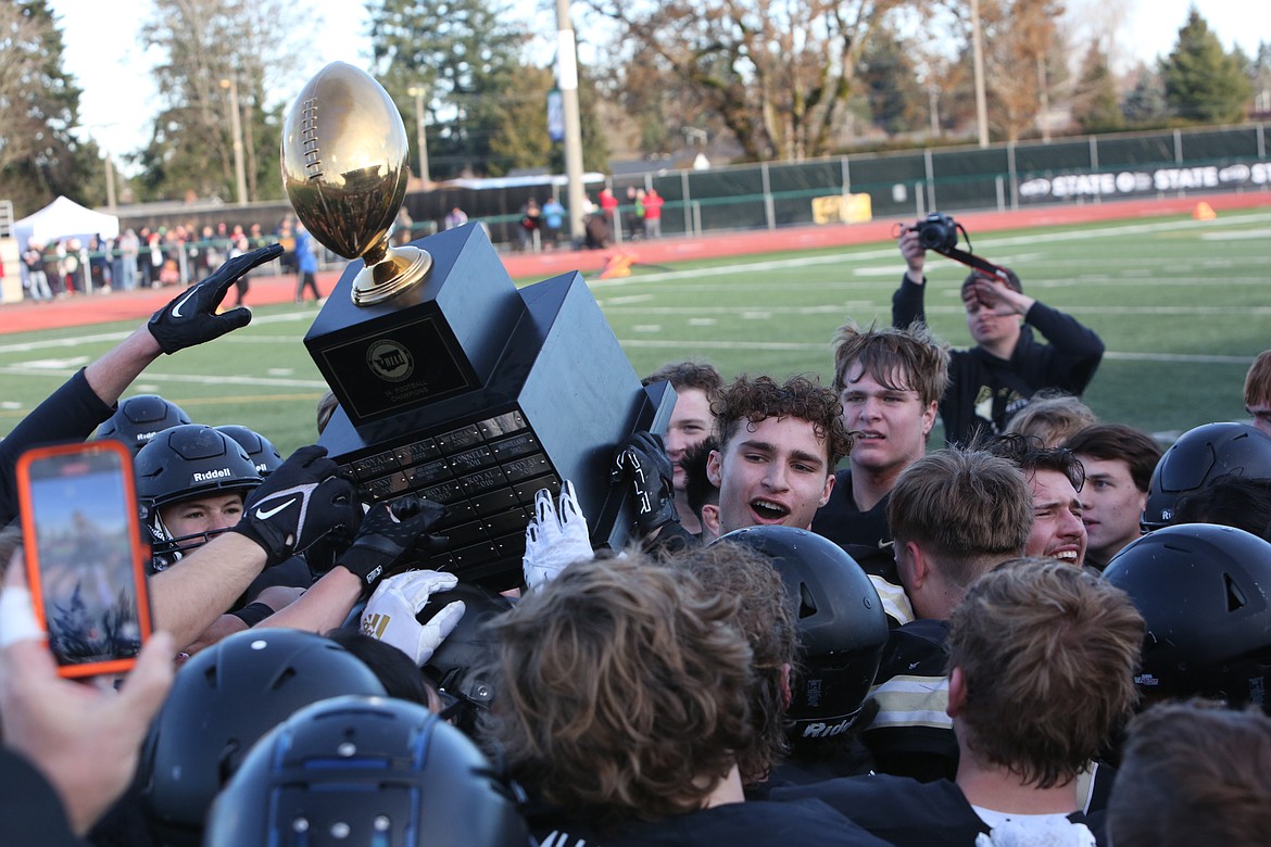 Royal receiver Edgar De La Rosa holds up the 1A state championship trophy while celebrating with teammates after the Knight’s win over Mount Baker on Saturday.