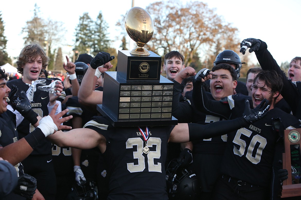 Royal running back Kaleb Hernandez uses the hollow insides of the state championship trophy to put on his head, posing for photos with his teammates.